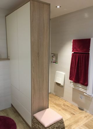 Ein Badezimmer mit Blick auf eine Dusche wo die Duschtrennwand als Schrankverbau ausgeführt ist