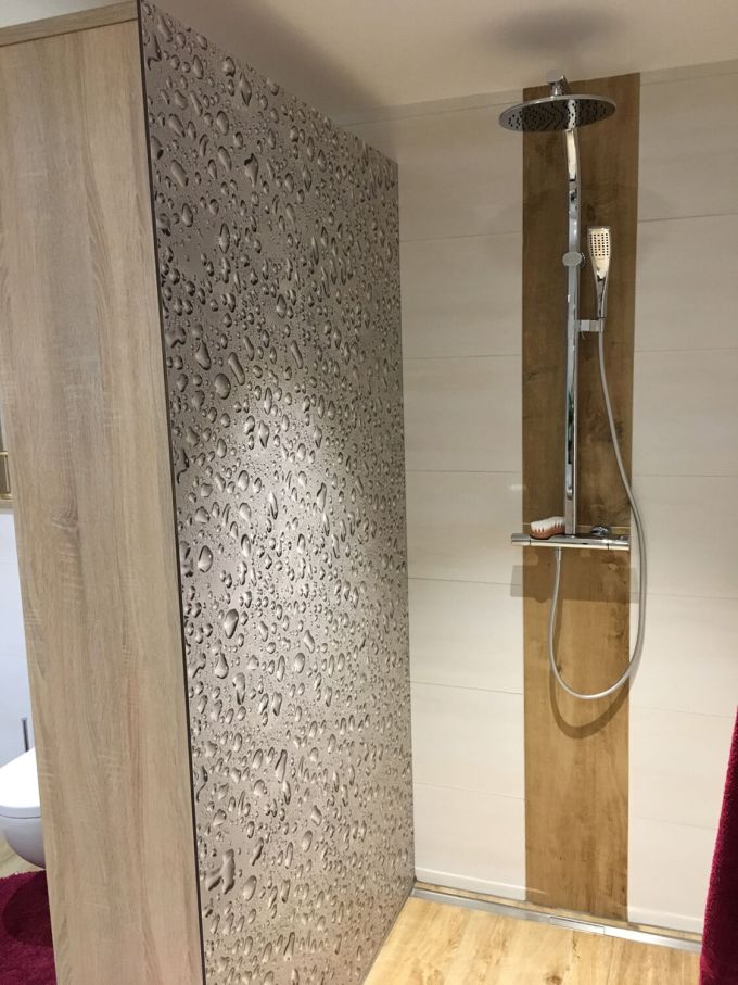 Ein Badezimmer mit Blick auf eine Dusche samt Duschtrennwand mit Wassertropfenmotiv